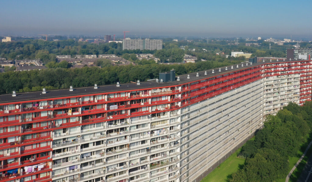 Birdview van Zaanstad met op de voorgrond een groot flatgebouw. De afbeelding verwijst naar hoe Firan met warmtedistributienetten zorgt voor duurzame warmte voor woningen en bedrijven.