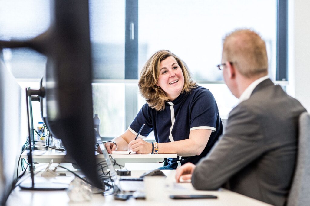 Collega's achter bureau in overleg over werkzaamheden Firan.